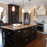 This Classic Kitchen has a combination of two finishes. A Painted Finish with a light glaze with the Island and Dish Cabinet in Maple with an espresso stain. Features include a custom wine rack, an apron front sink and a curved canopy to house an integrated range hood.