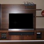 This Contemporary Wall Unit is suspended off the floor. Components are housed below the television and include an integrated speaker. The material is Quarter Sawn Walnut with a "stainless" laminate inlay for accents.