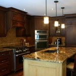 This Kitchen includes Walnut Cabinetry on the Perimeter with Integrated Fridge/Freezer, Range Hood Canopy and Dishwasher. The Island is Maple with a Stone Wash Finish. Beautiful granite countertops compliment both finishes and are accented with a Tumbled Marble Backsplash.